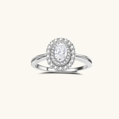 Sterling silver ring with oval moissanite center stone surrounded by double halo of sparkling stones on neutral background.