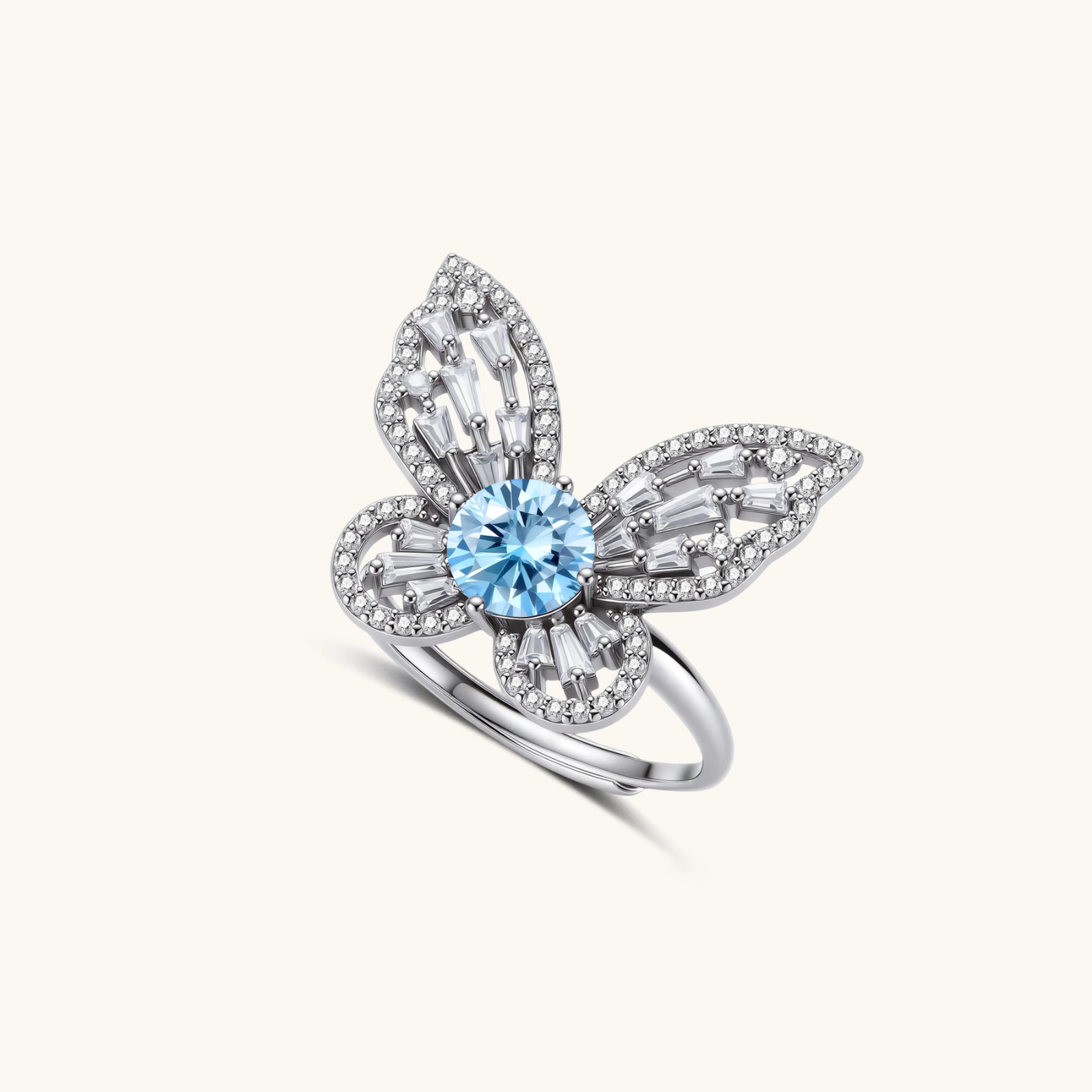242024256826200064.webp Sterling silver ring with blue moissanite center stone surrounded by clear stones in butterfly wing pattern on white background