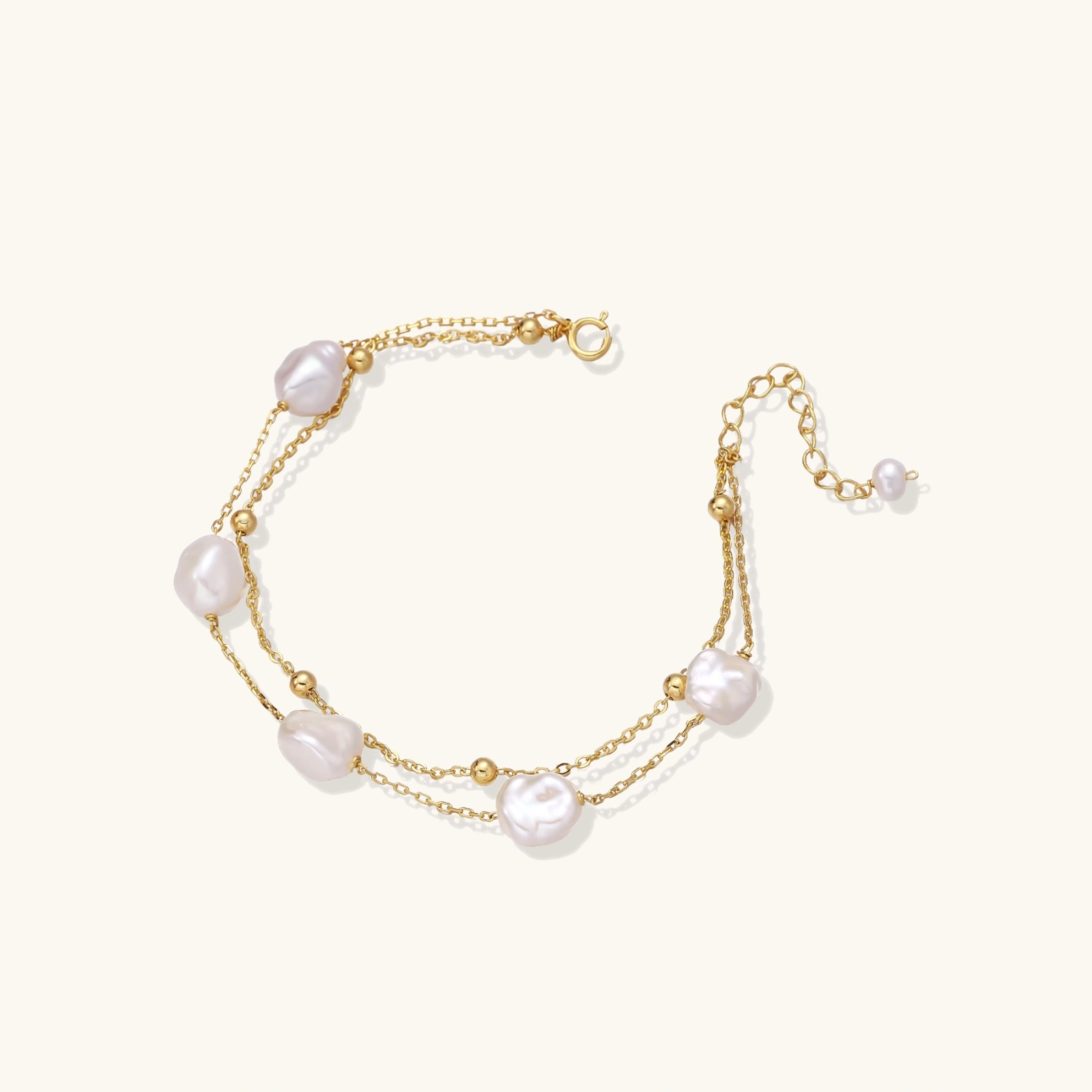baroque pearl layered bracelet Double-strand gold bracelet with irregular baroque pearls and smooth freshwater pearls on cream background.