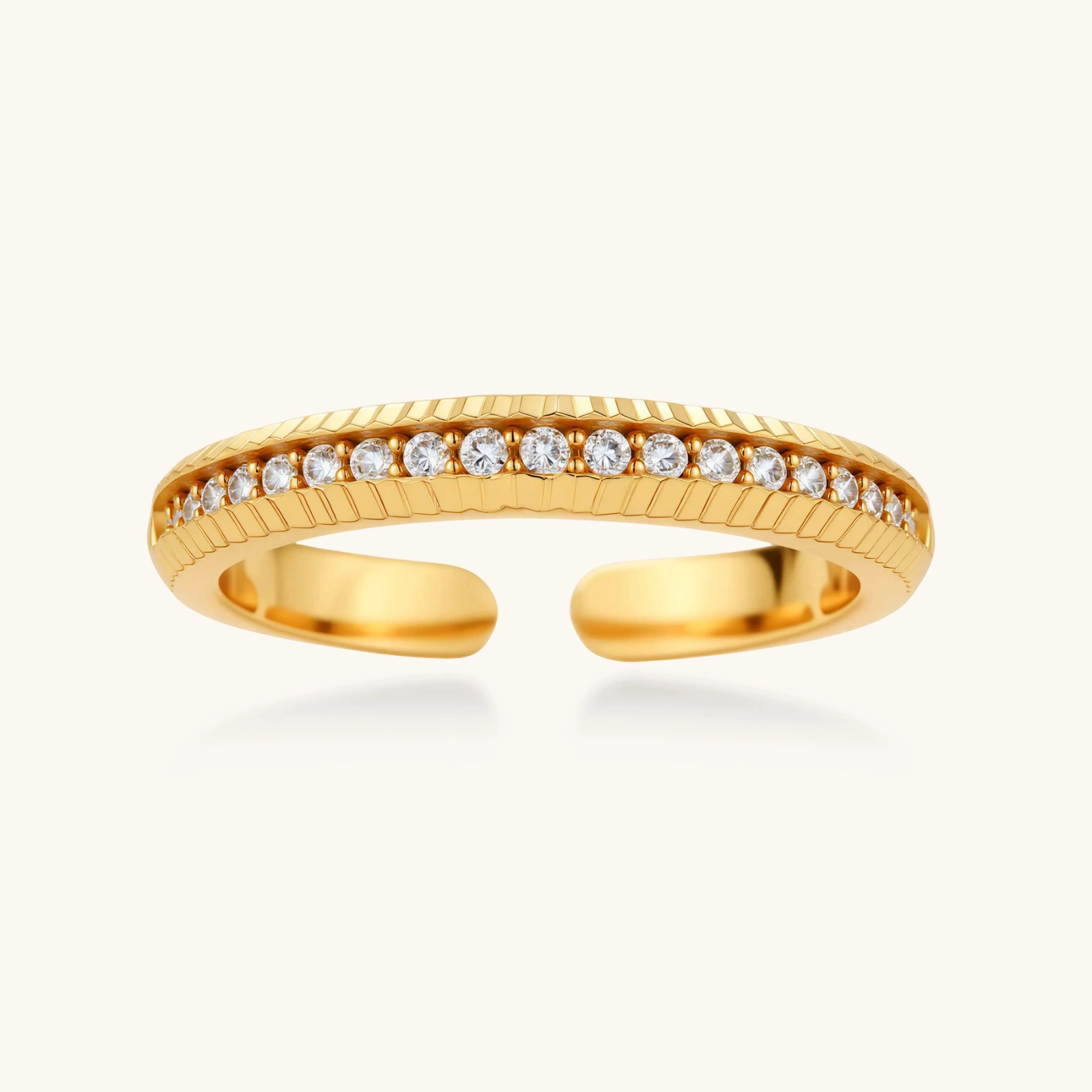 273951840185798656.webp Adjustable gold-plated ring with row of sparkling crystals on ribbed band, shot against cream background