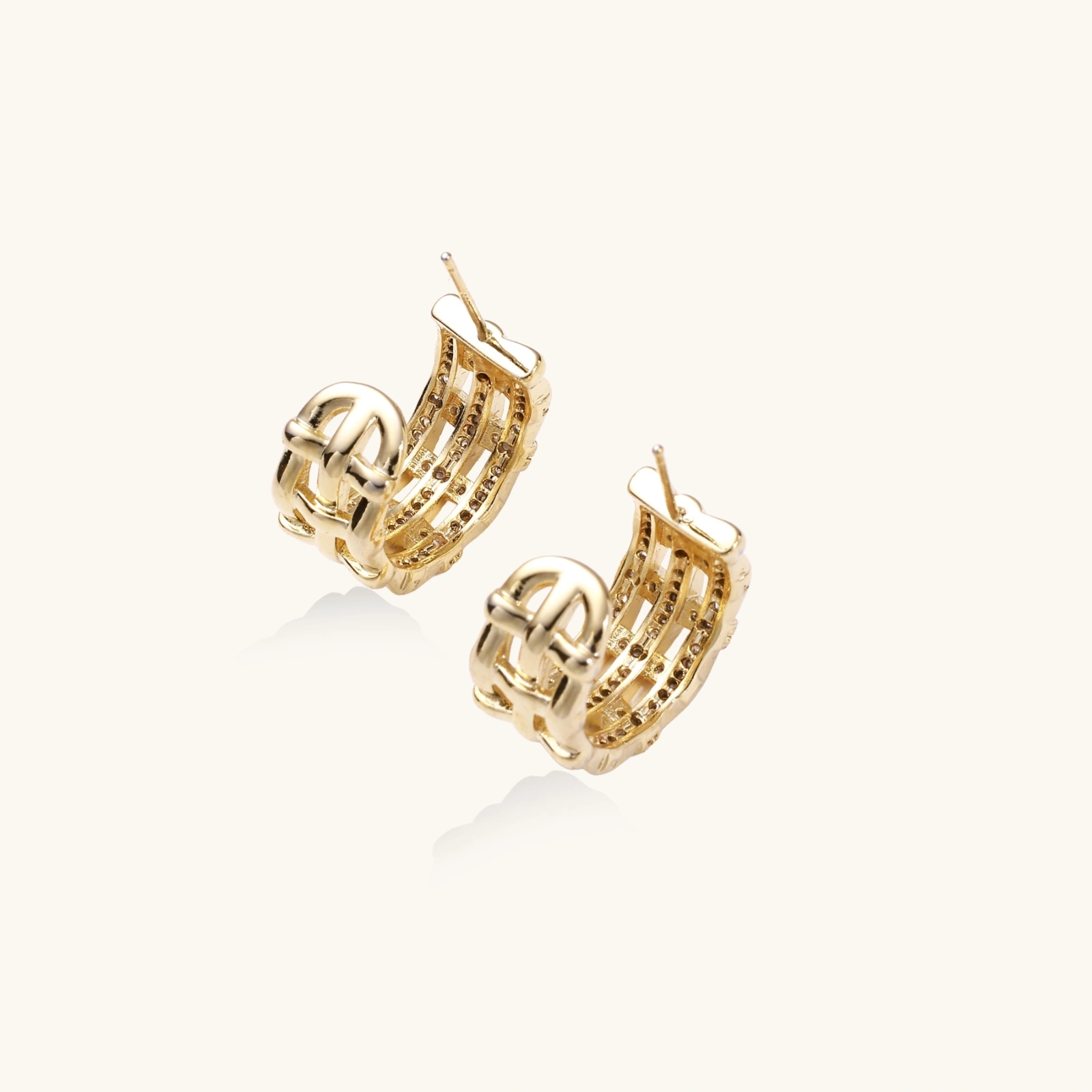 242422537213399040.webp Gold-plated geometric hoop earrings with basket-weave lattice design and pavé crystal accents on cream background
