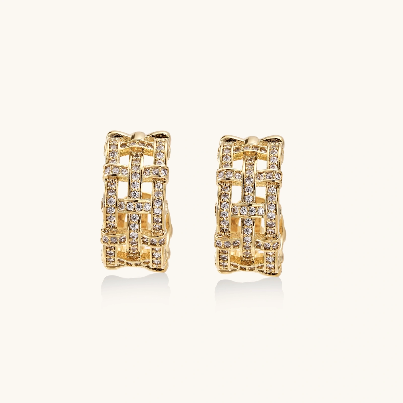 242422549506904064.webp Gold-plated geometric hoop earrings with basket-weave lattice design and pavé crystal accents on cream background
