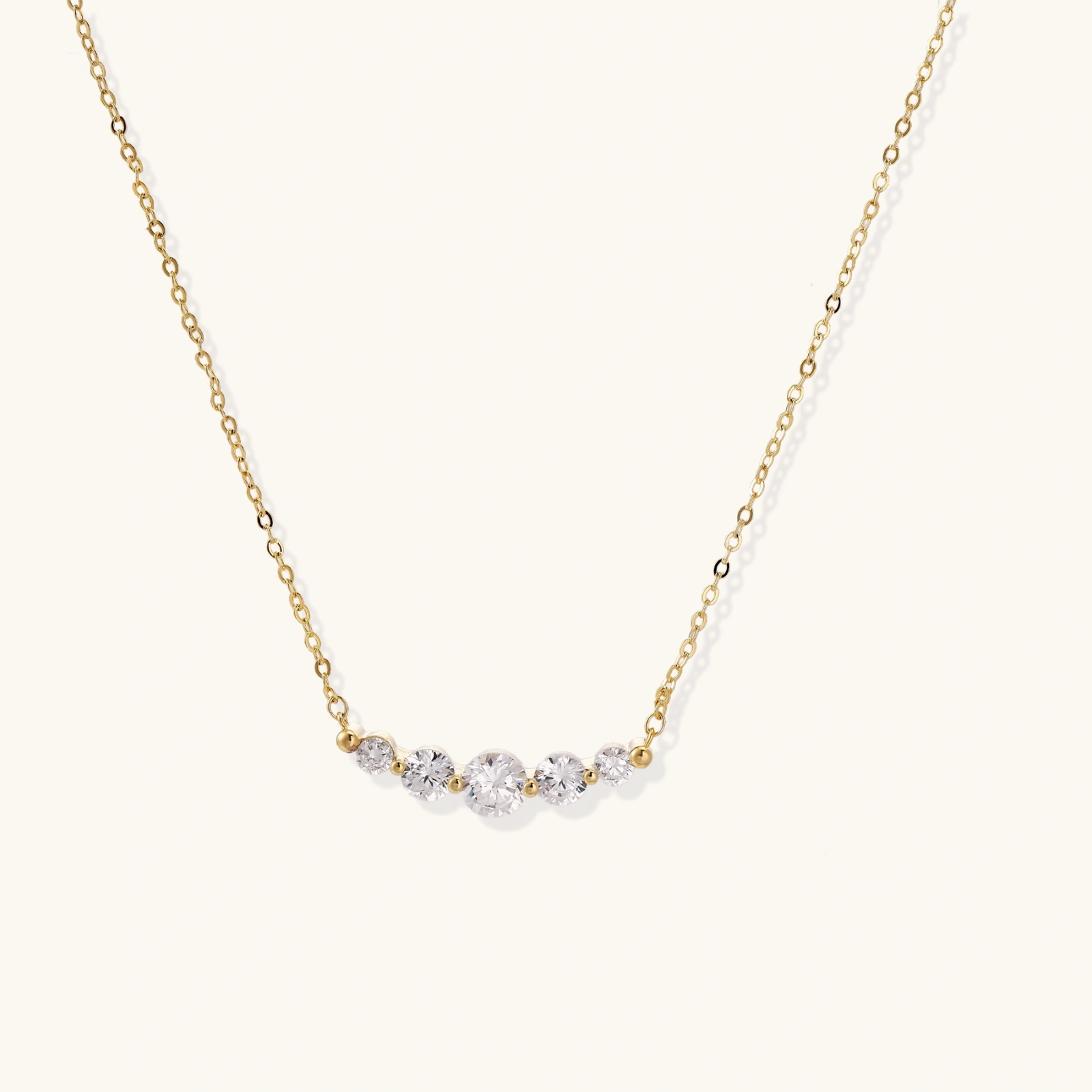 242424096548876288.webp Delicate 14K gold-plated necklace with five graduated zirconia stones arranged in a curved arc on fine chain