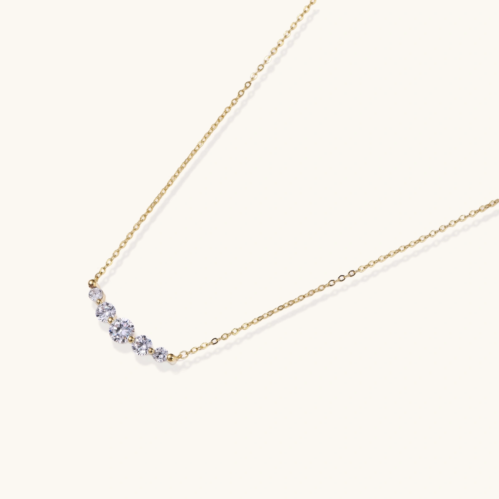 242424096632762368.webp Delicate 14K gold-plated necklace with five graduated zirconia stones arranged in a curved arc on fine chain